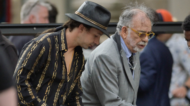 Shia LaBeouf in costume walking alongside a disheveled Francis Ford Coppola