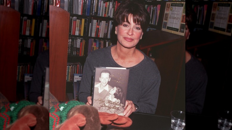 Tina Sinatra displaying a copy of her memoir at a book signing.