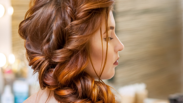 Woman with red hair styled into a loose French braid 