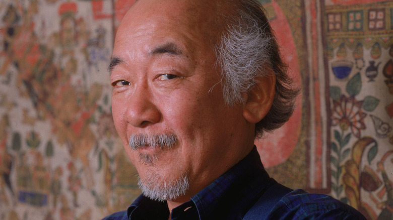 Pat Morita in front of a tapestry