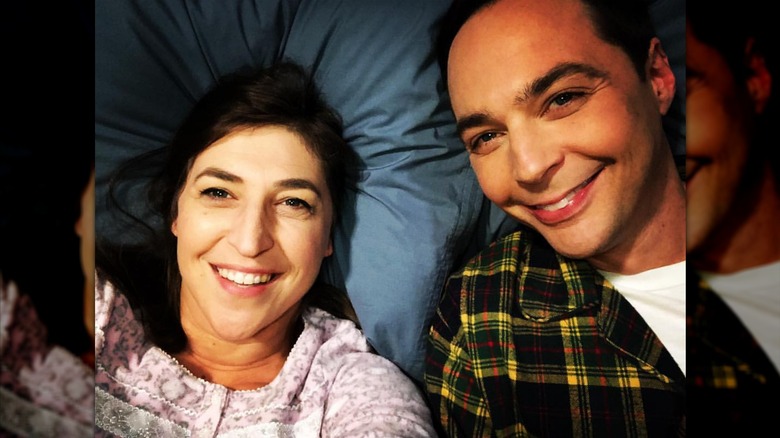Mayim Bialik and Jim Parsons taking a selfie in a bed.