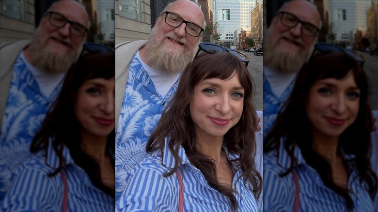 Lauren Lapkus and Brian Posehn posing for a selfie beside a city street.