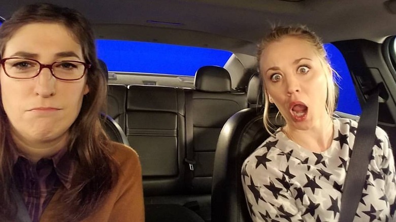 Mayim Bialik and Kaley Cuoco seated in a car.