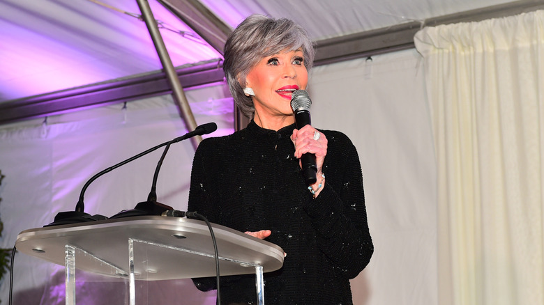 Jane Fonda speaks from a podium at a charity benefit