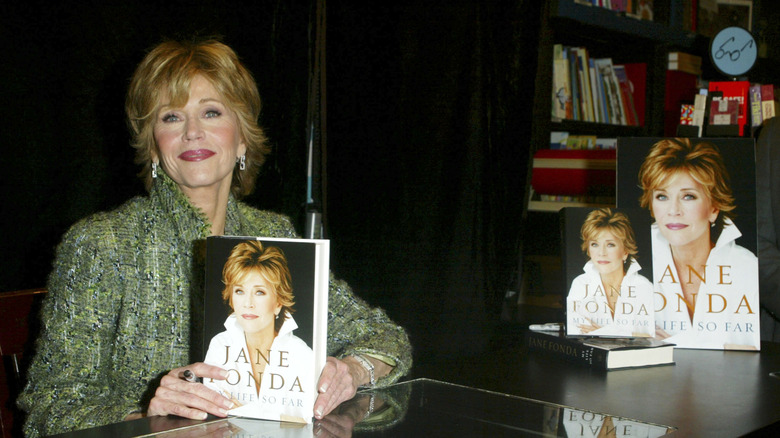 Jane Fonda holds her memoir at a promotional book event