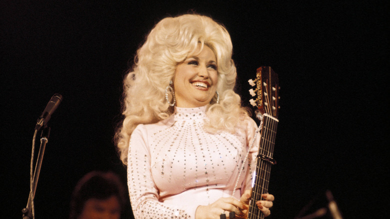 Dolly Parton on stage holding a guitar