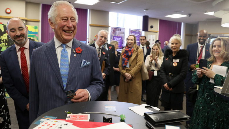 King Charles III laughing at a table of cards