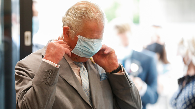 King Charles III having a fumble with a mask during the Covid-19 pandemic