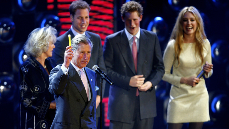 King Charles III speaking while lifting a glowstick into the air