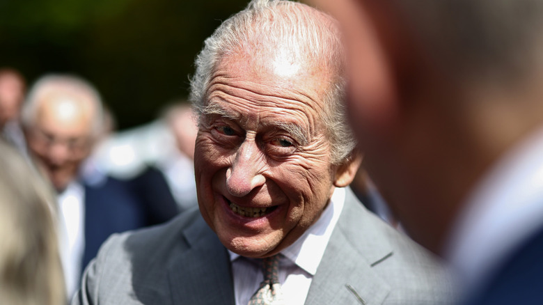 King Charles III smiling mischievously
