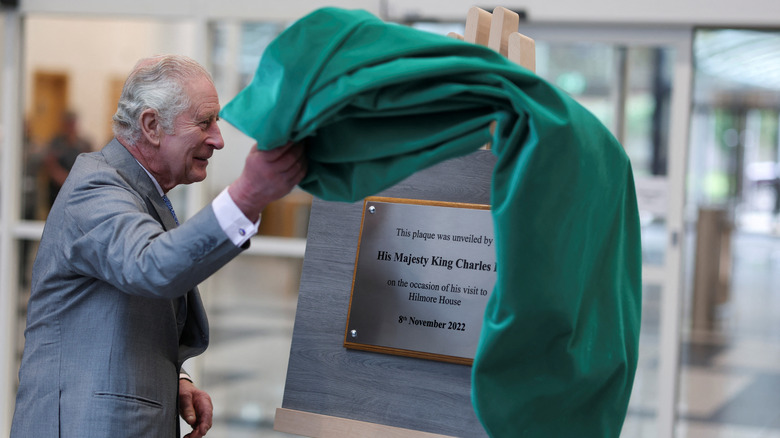 King Charles III unveiling a plaque with a flourish