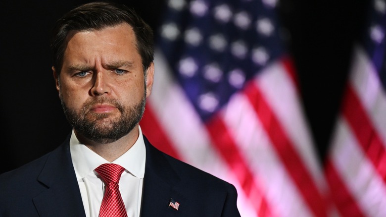 JD Vance stands in front of an American flag