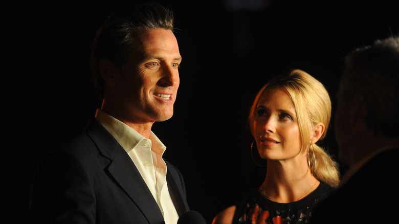Photographed in darkness, Gavin Newsom smiles with Jennifer Newsom looking up at him.