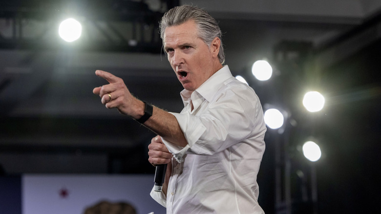 Gavin Newsom pointing onstage in a white shirt