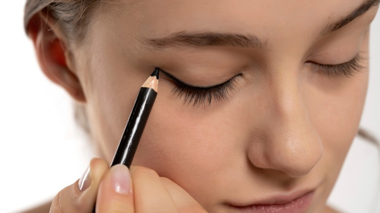Woman applying pencil eyeliner