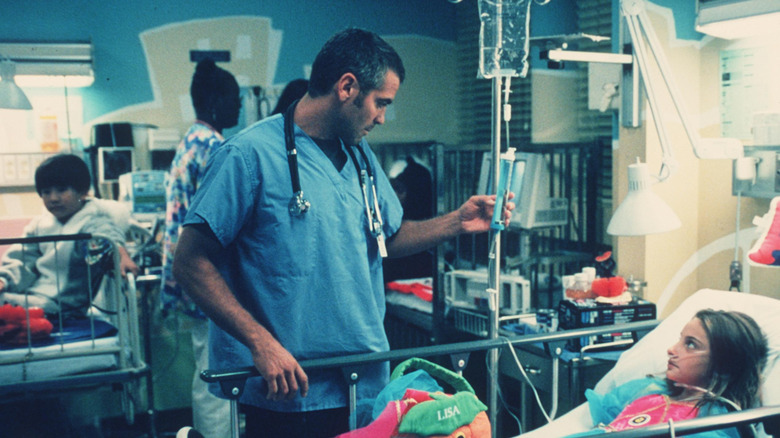 George Clooney in hospital scrubs checking on a child patient for his role on ER