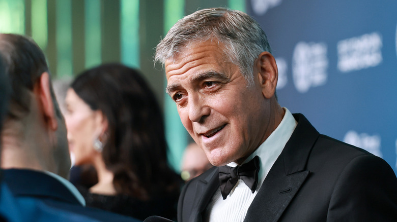 George Clooney wearing a tuxedo and smiling while being interviewed