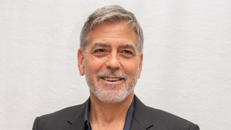 George Clooney stands against a white wall
