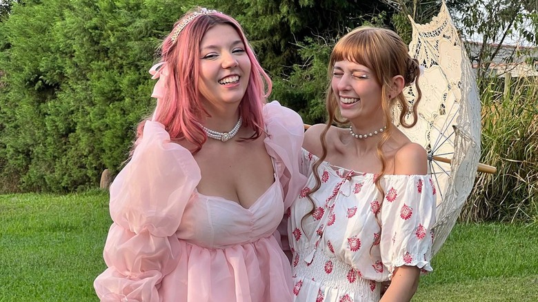 Two women laughing outside in pink dresses