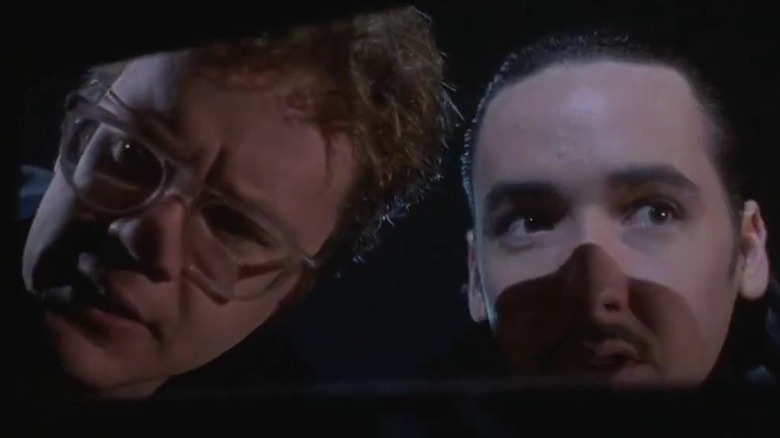 Tim Robbins and John Cusack peering into a car window in Tapeheads.