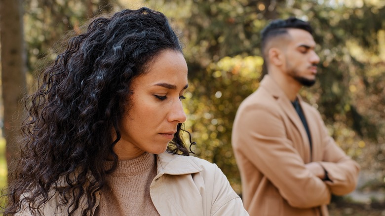 couple standing apart with arms crossed