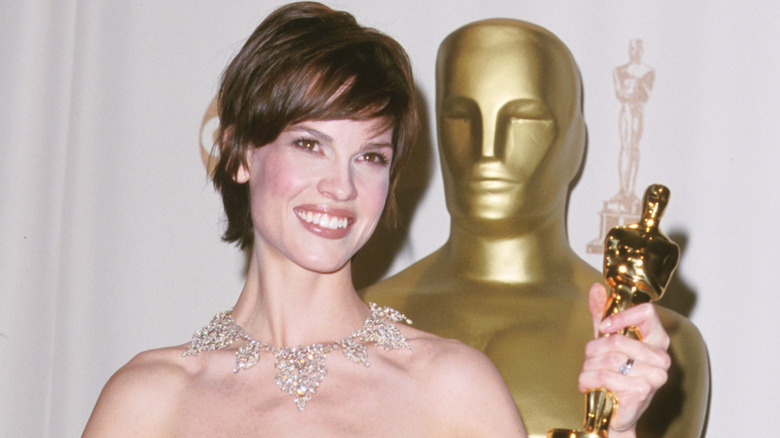 Hilary Swank smiling while holding her Oscar