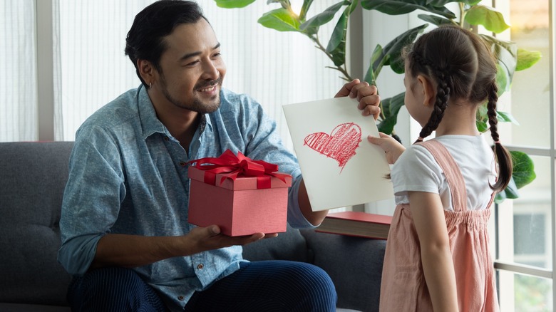 Little girl giving dad a card and present
