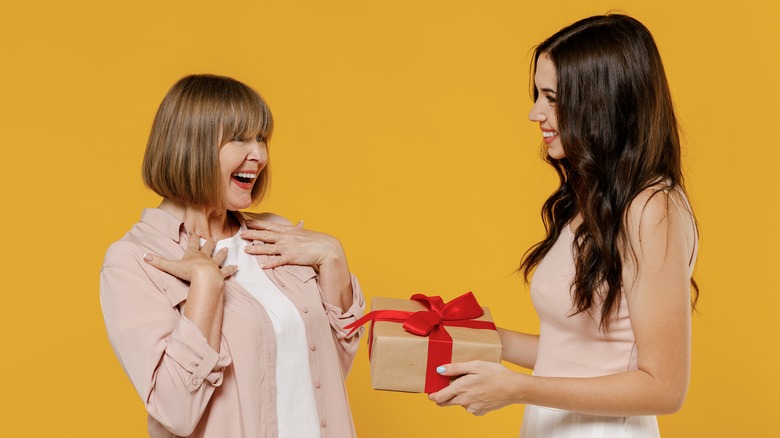 Woman giving her mother a gift, orange background
