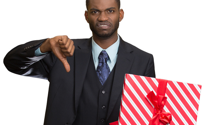 man holding gift and giving thumbs down