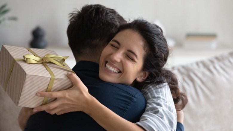 woman hugging man with gift in hand