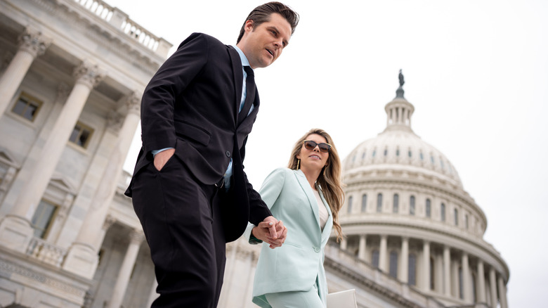 Matt Gaetz and Ginger Luckey Gaetz holding hands in suits and walking