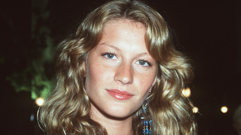 Young Gisele Bündchen smiling at a benefit in 2000