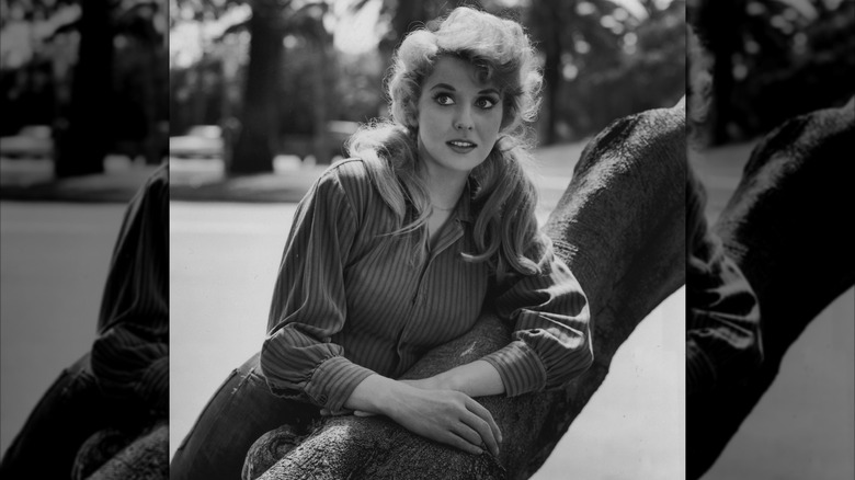 Donna Douglas in a striped shirt with pigtails by a tree