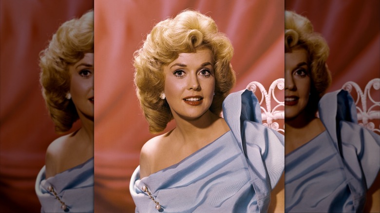 Donna Douglas in a blue off-the-shoulder gown before a pink backdrop