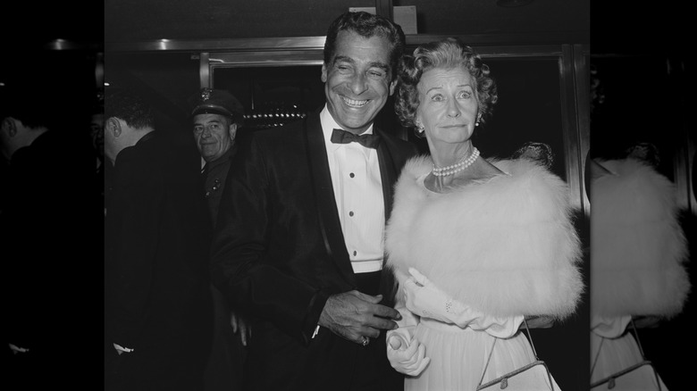 Irene Ryan at a premiere in a white fur sash with a man in a tuxedo