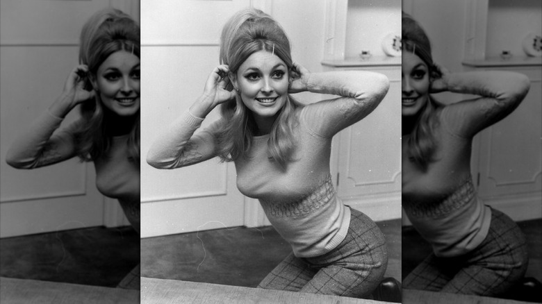 Sharon Tate in a tight shirt and plaid trousers with her hair teased up