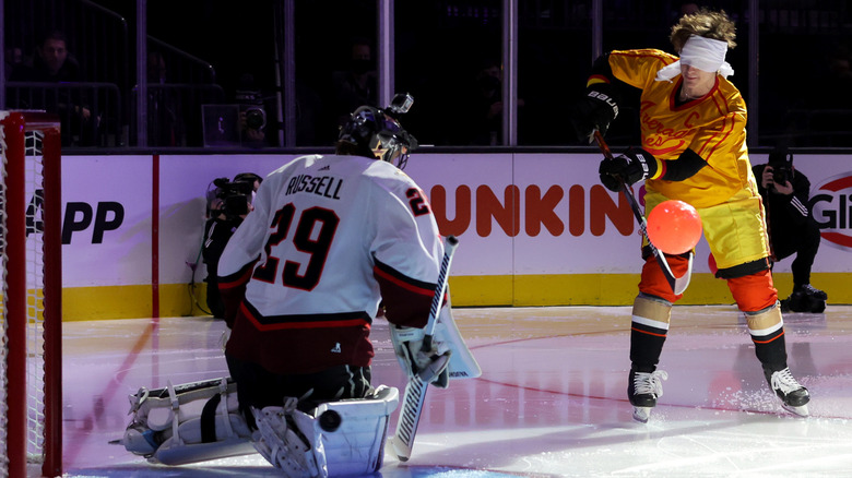 Wyatt Russell (left, in white jersey with "Russell" on the back, number 29) trying to defend a goal from a blindfolded player during the 2022 NHL All-Star Game
