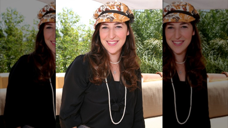 Mayim Bialik smiling and wearing a hat