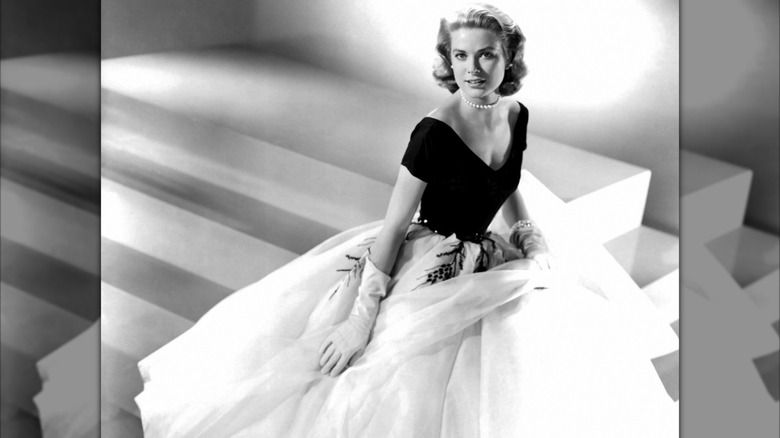 Grace Kelly posing in a black and white gown, wearing pearls, on the set of "Rear Window"