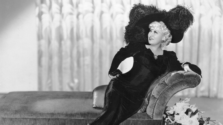 Mae West (1893 - 1980) reclining on a chaise longue in a promotional portrait for 'Klondike Annie', directed by Raoul Walsh, 1936. West was co-writer of the screenplay.