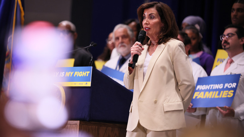 Gov. Kathy Hochul speaking into a microphone, surrounded by people