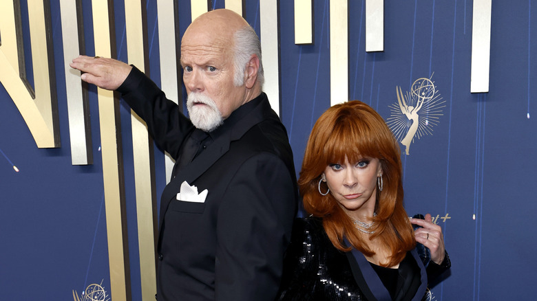 Rex Linn and Reba McEntire posing in front of Emmys backdrop