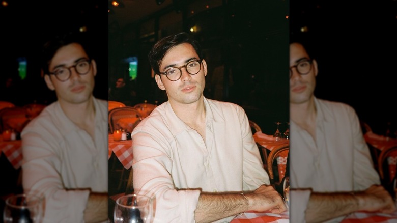 Harper Peck wearing glasses and leaning over a restaurant table posing