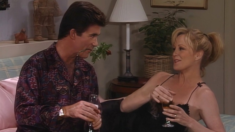 Alan Thicke looking at Joanna Kerns with a rose in his mouth on a bedroom set
