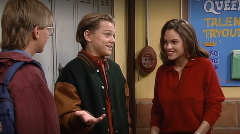 Hilary Swank smiling at Leonardo DiCaprio beside lockers in a "Growing Pains" episode.