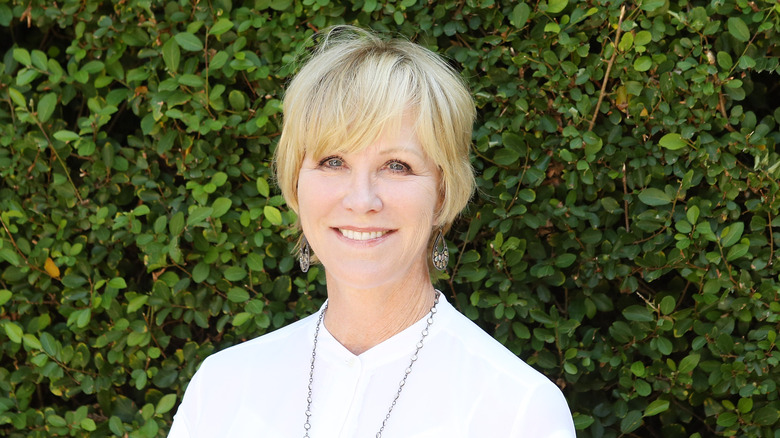 Joanna Kerns smiling while posing in a white blouse with silver jewelry