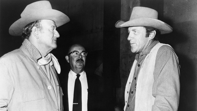 John Wayne and Jim Arness talking, both in Western wear