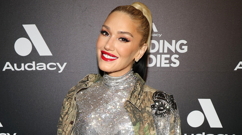 Gwen Stefani smiling while posing on the red carpet in a sparkly outfit