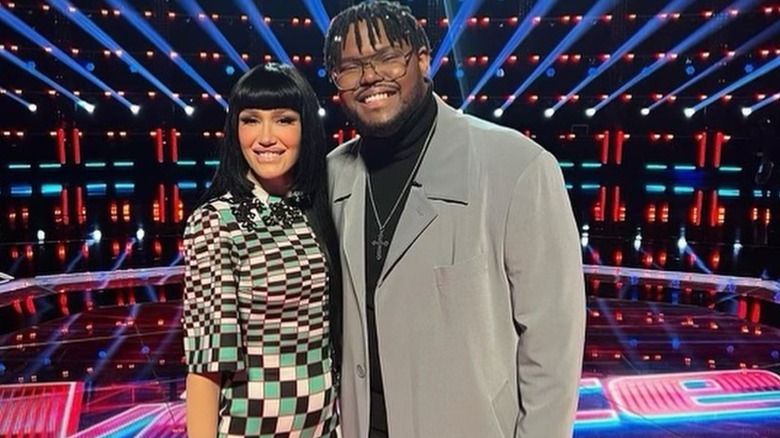 Gwen Stefani in checkered dress and dark wig with The Voice contestant Justin Aaron
