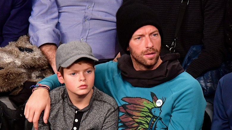 Chris Martin and Moses Martin sitting together at a basketball game in Barclays Center in 2016